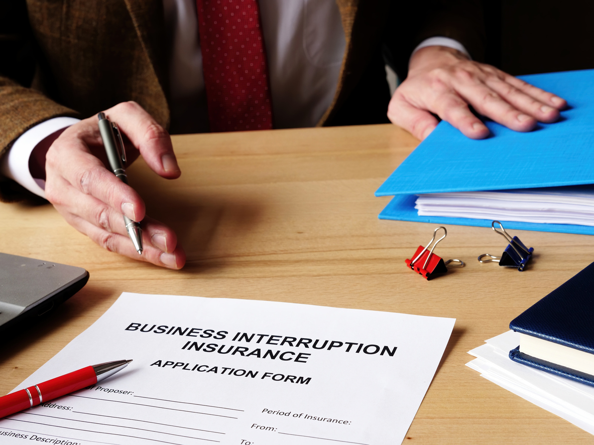 Agent offers business interruption insurance application papers.