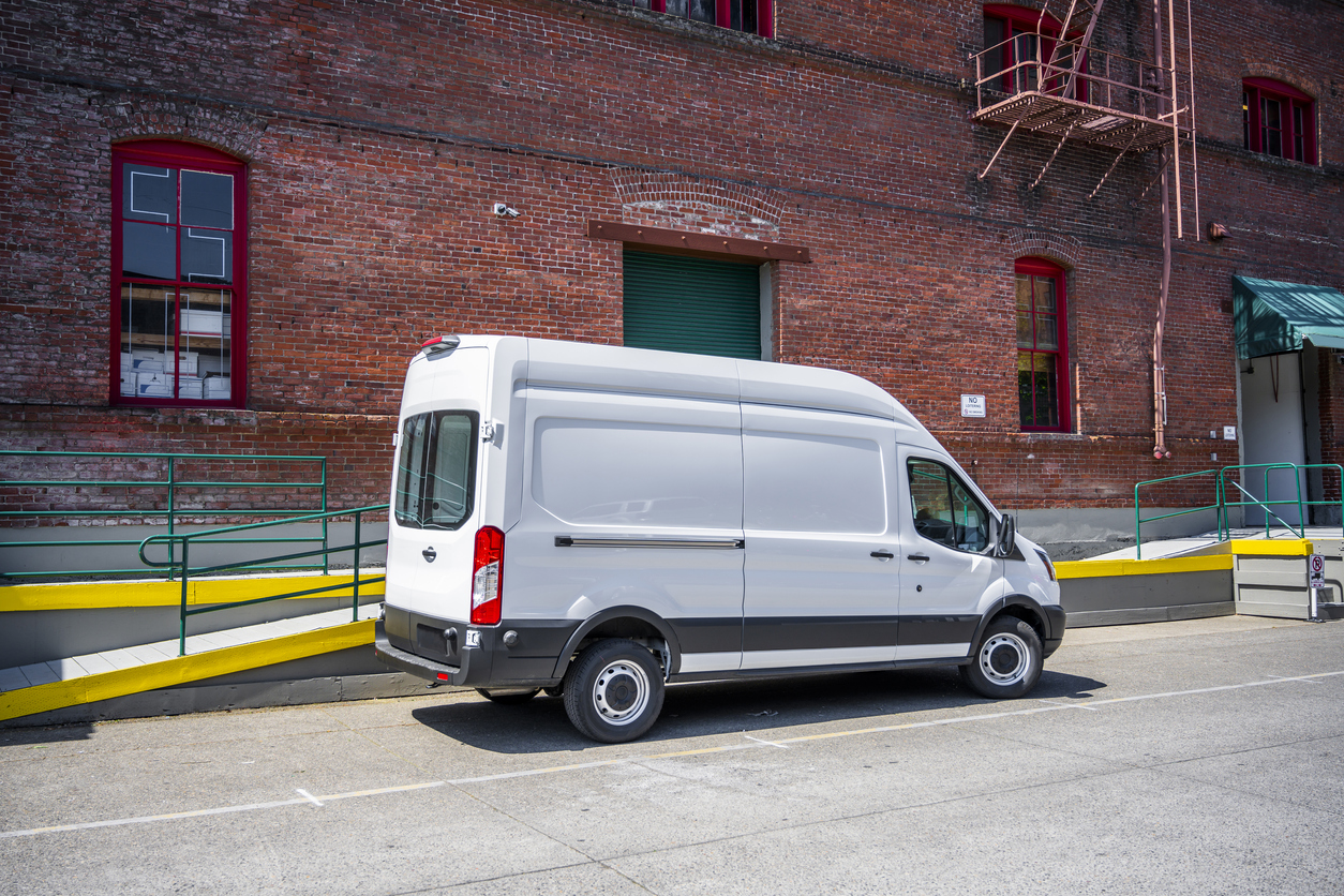 White compact popular cargo mini van for local deliveries and business standing on the warehouse parking lot