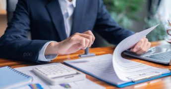 Man carefully reviewed finance agreements and contract documents with his client, discussing loan, mortgage, investment opportunities, credit terms, and tax implications for their business.