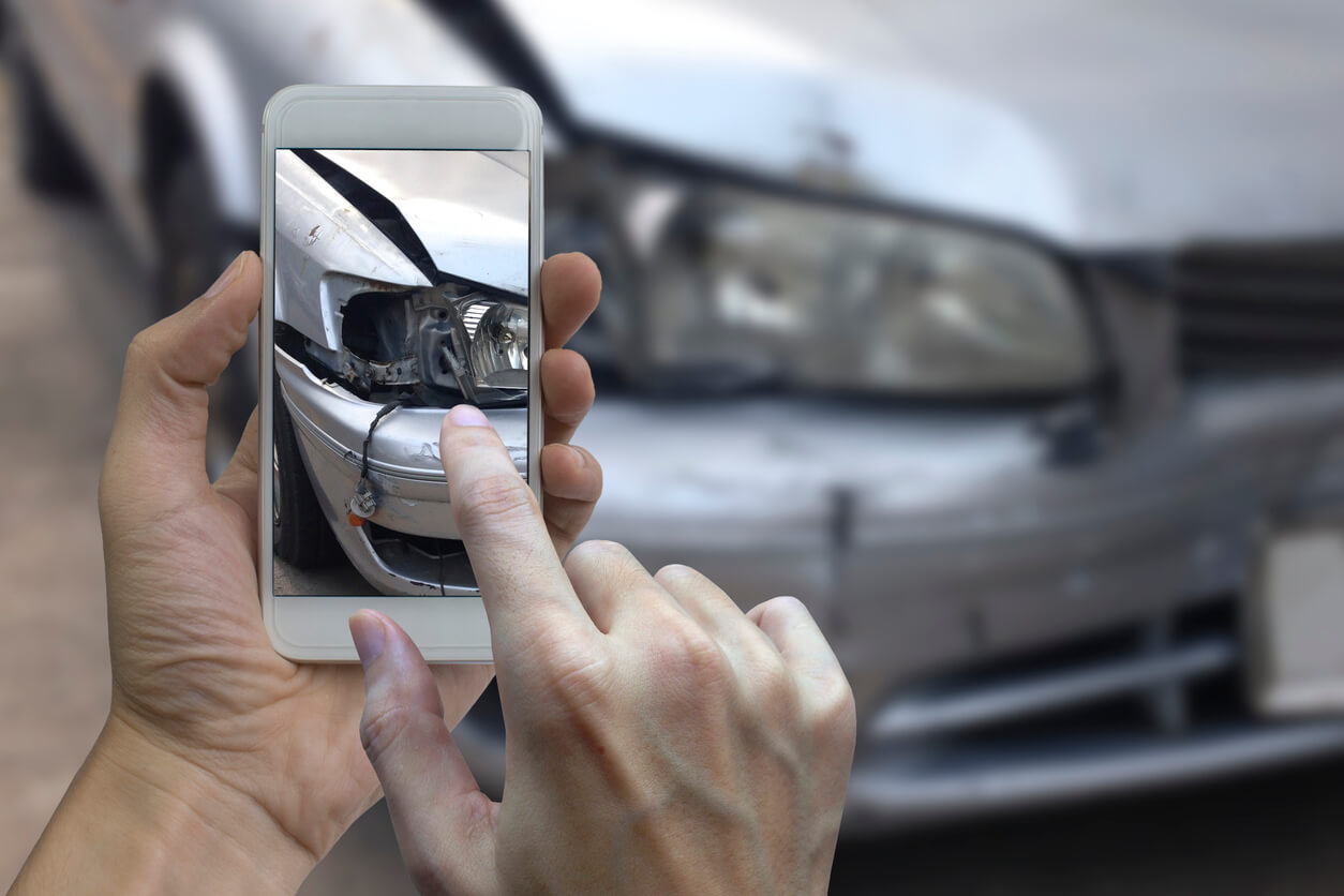 Hand holding smart phone take a photo at The scene of a car crash, car accident for insurance.