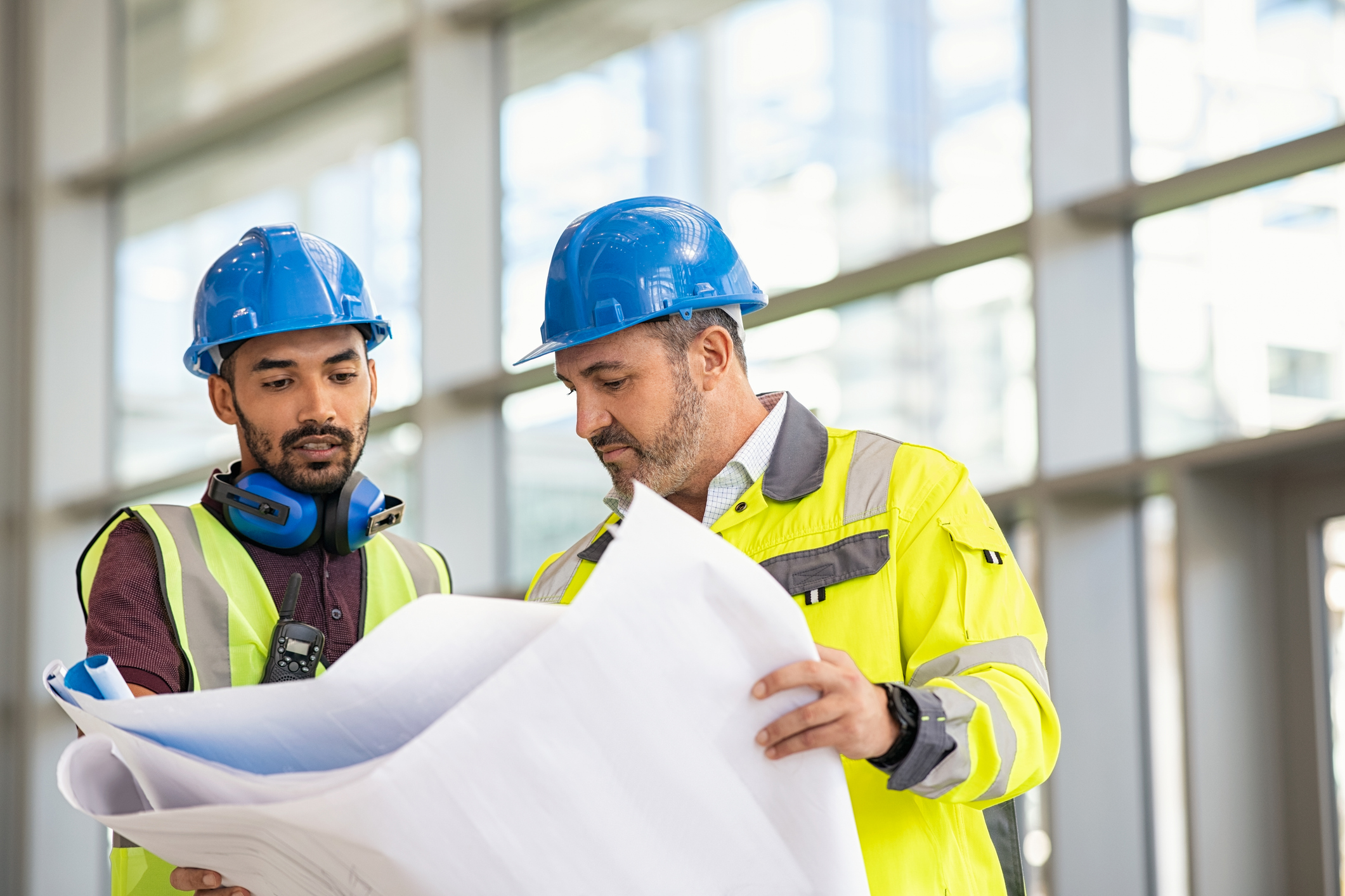 Construction site worker and engineer discussing on blueprint project