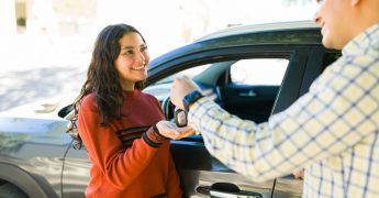 Father happily passing car keys to his teenage daughter