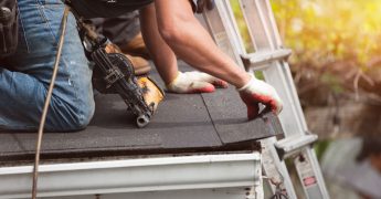 roofers installing a new roof on residential home. weatherlock material and brown asphalt roofing shingles