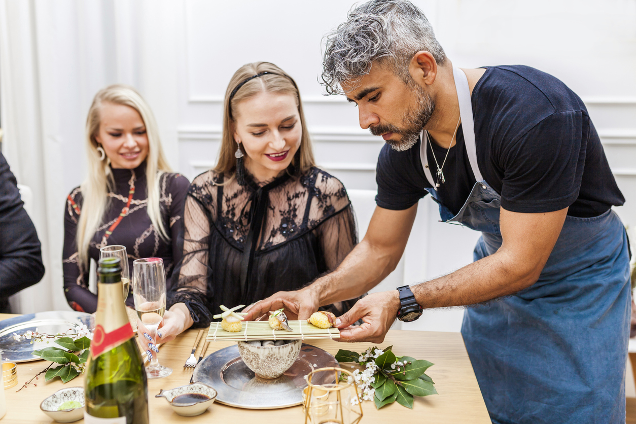 Latin cook serving food to clients during private dinner